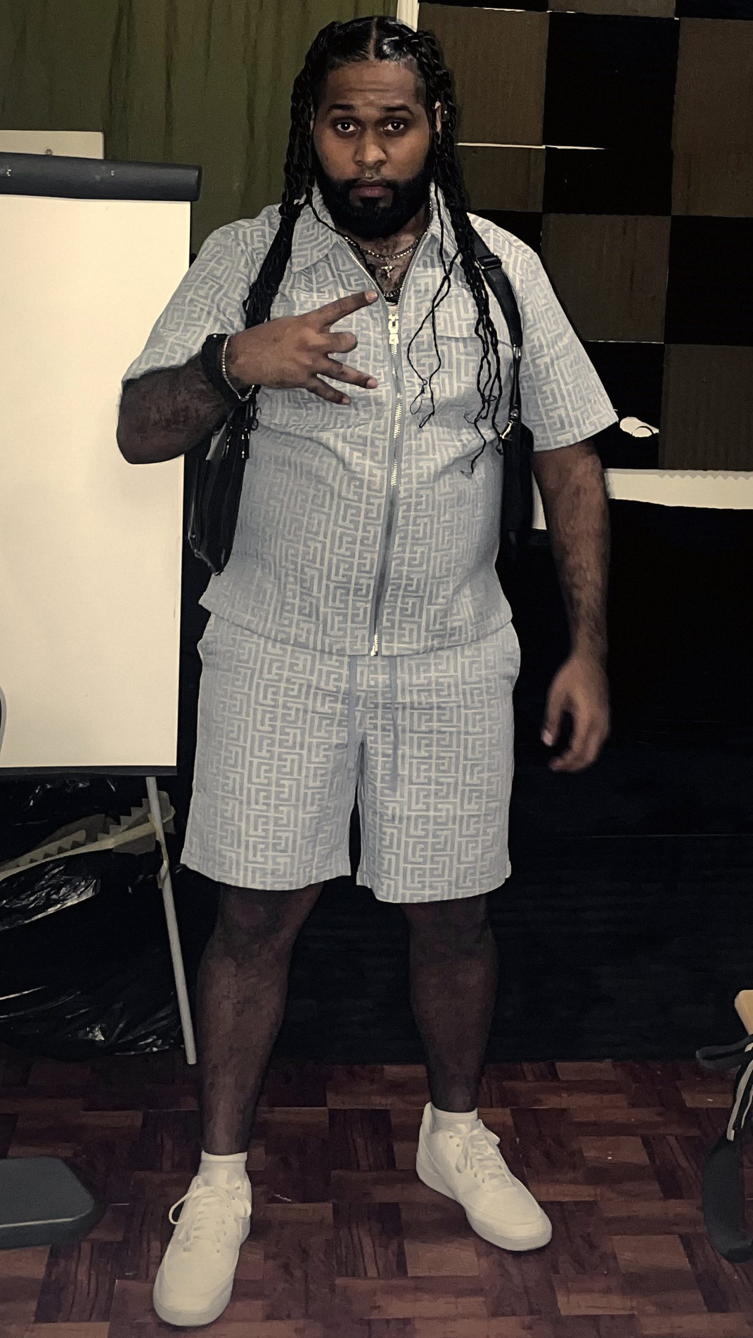 Vinci Smokes standing in the studio, throwing up a hand sign