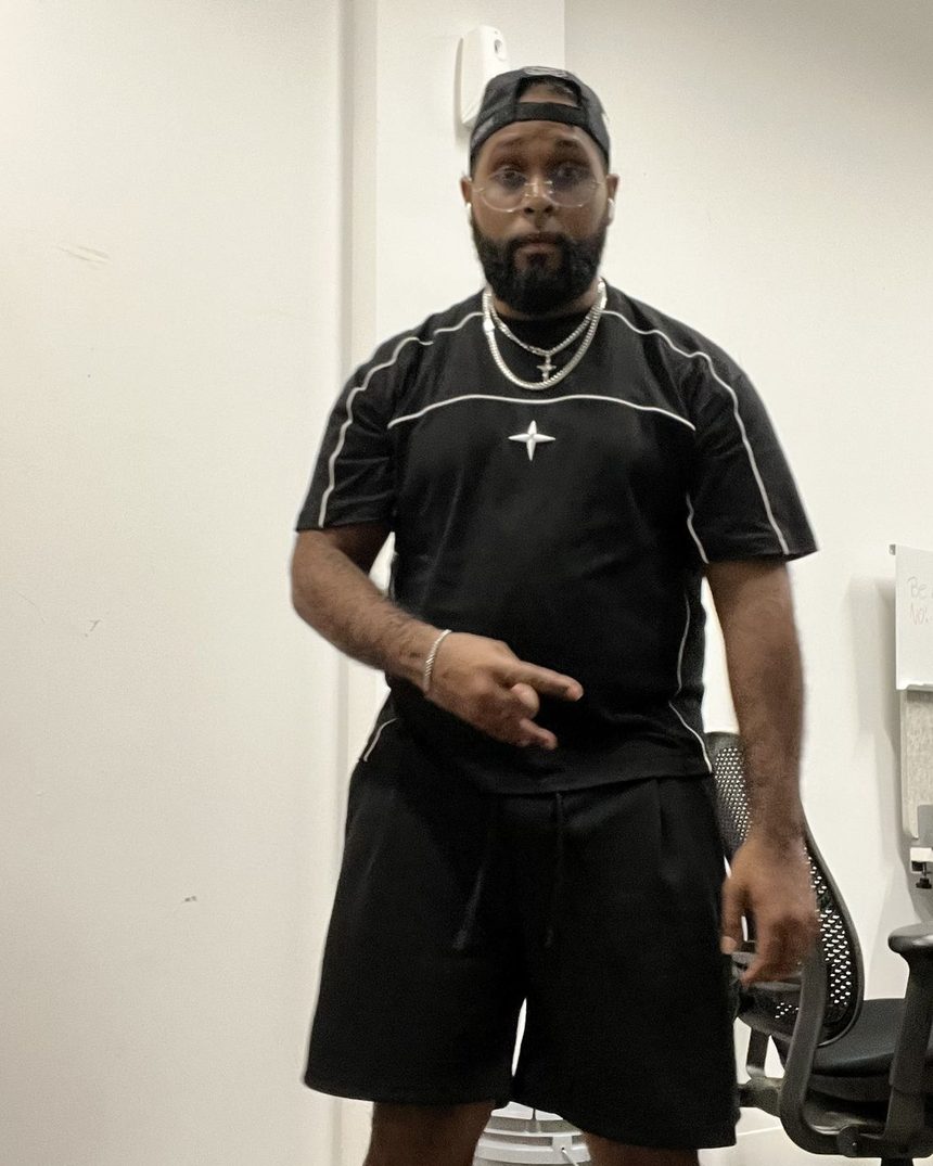 Vinci Smokes standing in a white room, black fit